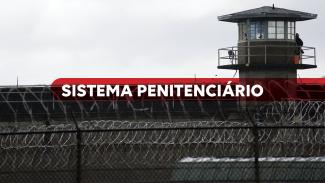Imagem mostra o muro de uma penitenciária com uma guarita no alto, à direita. Ao centro há a expressão Sistema Prisional escrito em branco sobre um tarja vermelha.