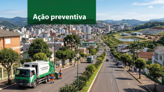 Banner horizontal com foto aérea de uma área urbana. Em primeiro plano, um caminhão de coleta de resíduos e trabalhadores uniformizados realizam o recolhimento de lixo em uma avenida arborizada. A via é dividida por canteiro central com vegetação, cercada por casas, prédios e áreas verdes. Ao fundo, aparecem morros e a paisagem da cidade. No canto superior esquerdo, sobre uma faixa verde translúcida, está o texto “Ação preventiva”. 