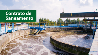 Banner horizontal com foto de uma estação de tratamento de esgoto ao ar livre. A imagem mostra grandes tanques circulares de concreto, cheios de água turva em processo de tratamento. Há estruturas metálicas azuis e passarelas que atravessam os tanques, além de tubos e equipamentos industriais posicionados acima da água. No canto superior esquerdo, sobre um retângulo verde, o texto “Contrato de Saneamento”.