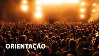Banner horizontal com foto, em filtro laranja, de uma plateia que assiste a um show. Há várias pessoas, de costas para a foto. Algumas estão com braços levantados. No palco, à frente, há luzes amarelas que iluminam o público. No canto inferior esquerdo, o texto “Orientação”, em fonte branca. 