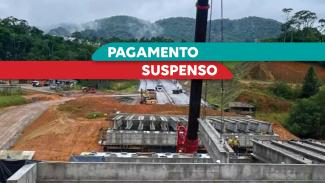 Imagem mostra obras em uma rodovia. Ao centro sobre tarjas verde e vermelha, está escrito “pagamento suspeito” 