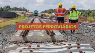 Banner horizontal com foto de uma ferrovia em construção. Em primeiro plano, aparecem trilhos recém-instalados sobre estruturas de concreto e brita. Ao centro da imagem, dois profissionais com capacetes e coletes de segurança caminham ao longo da via férrea, observando e apontando para a área da obra. Uma faixa vermelha semitransparente destaca o texto “Projetos ferroviários” ao centro. 