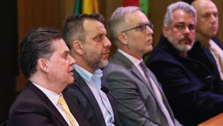 Foto de cinco autoridades, uma ao lado da outra, durante a reunião. Entre os presentes, o diretor-geral de Controle Externo, Sidney Tavares Júnior.