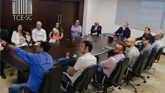 Foto de reunião na qual foi apresentado estudo sobre telessaúde. Na mesa, no lado direito da foto, estão o presidente conselheiro Herneus De Nadal, os conselheiros Dado Cherem, Adircélio de Moraes Ferreira Junior, o conselheiro-substituto Gerson dos Santos Sicca, mais quatro professores da UFSC,todos homens. Do outro lado da mesa, o conselheiro Wan-Dall, o diretor-geral da DGCE, Sideney Tavares Jr, a diretora adjunta da DGCE, Monique Portella