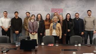 Banner horizontal que mostra 12 pessoas reunidas, lado a lado, em ambiente institucional. Entre os presentes, a conselheira substituta Sabrina Iocken, integrantes do TCE/SC e do Consea-SC. Todos sorriem e posam para a foto. Ao fundo, parede plotada com logo do TCE/SC.    