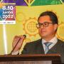 Desembargador Marcus Abraham aparece falando ao microfone em um púlpito. Ao fundo, um cartaz amarelo do Sétimo Congresso Internacional de Direito Financeiro