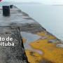 Imagem de um cais com bordas nos cantos superior esquerdo e inferior direito nas cores cinza e vermelha. Na margem inferior esquerda há o texto Porto de Imbituba na cor branca.